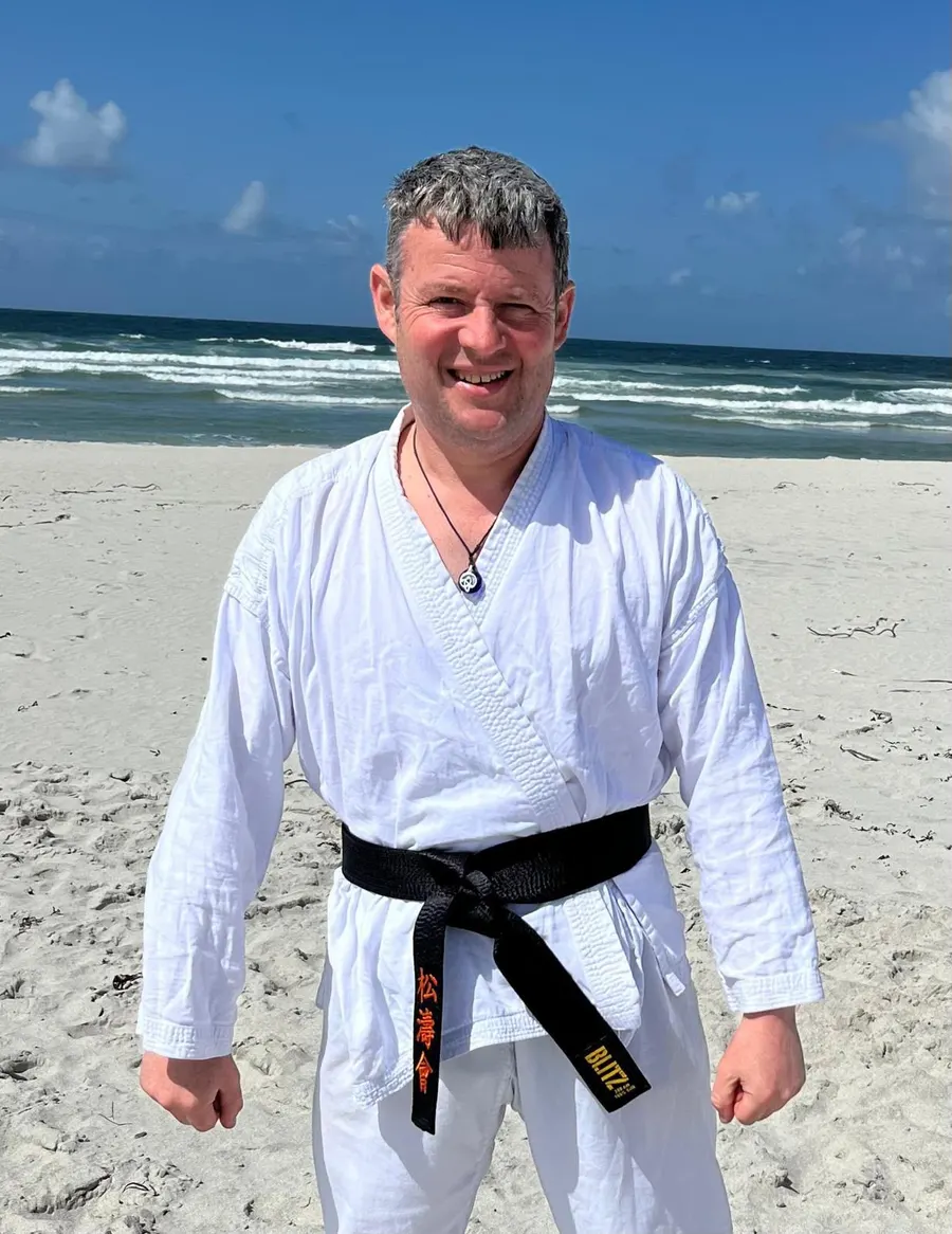 Iain MacDonald on a beach in a white gi